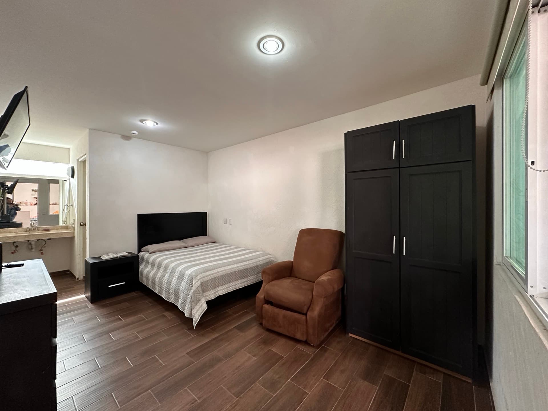 Spacious room with bed, armchair and wardrobe